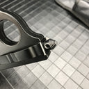 A close-up of the threaded glass breaker tip on the handle of a black 1918 U.S. knuckle duster OTF knife, displayed on a dark grid background.