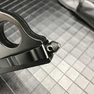 A close-up of the threaded glass breaker tip on the handle of a black 1918 U.S. knuckle duster OTF knife, displayed on a dark grid background.