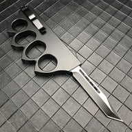 An open 1918 U.S. style black knuckle duster OTF knife with a silver blade, showing the silver pocket clip on the back of the handle, displayed on a dark grid background.