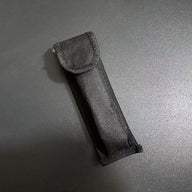 A close-up of a black nylon carrying sheath designed for a balisong butterfly knife, displayed on a dark background.