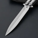 An extreme close-up of a balisong butterfly knife blade, showing the brushed stainless steel finish and sharp tip on a dark background.