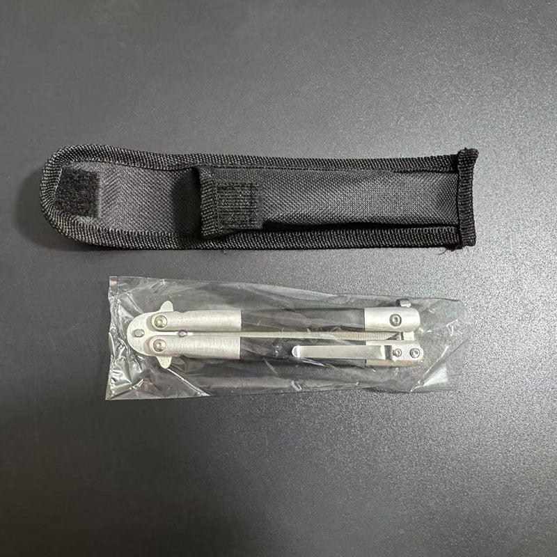 A black nylon sheath and a closed balisong butterfly knife sealed inside a plastic bag, displayed on a dark background.