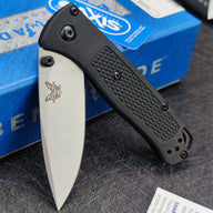 An open Benchmade folding knife with a black handle and silver blade, displayed with a blue box and an Axis lock sticker.