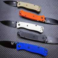 Five Benchmade folding knives with tan, orange, white, black, and blue handles, featuring black blades, stacked horizontally on a textured surface.