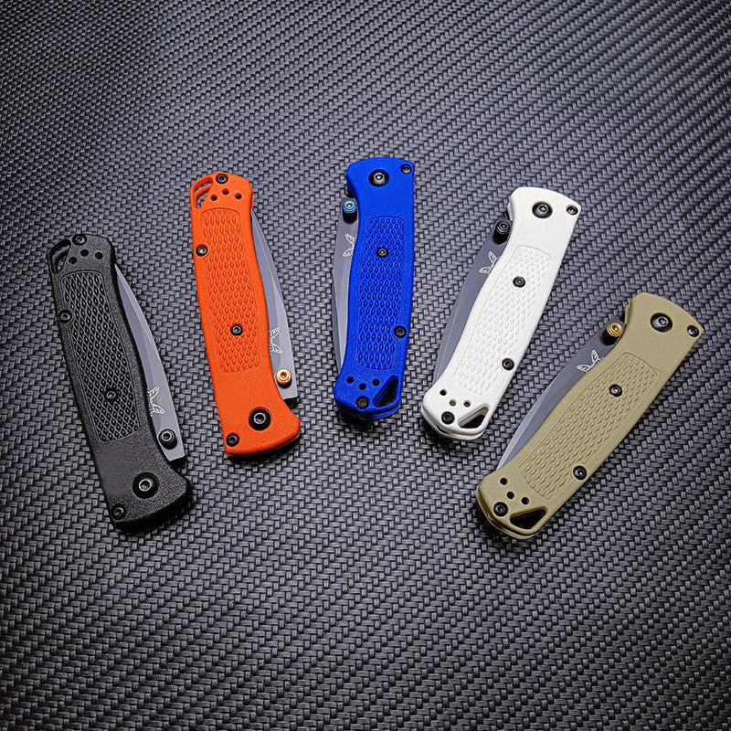 Five closed Benchmade folding knives with black, orange, blue, white, and tan handles, displayed on a textured surface.