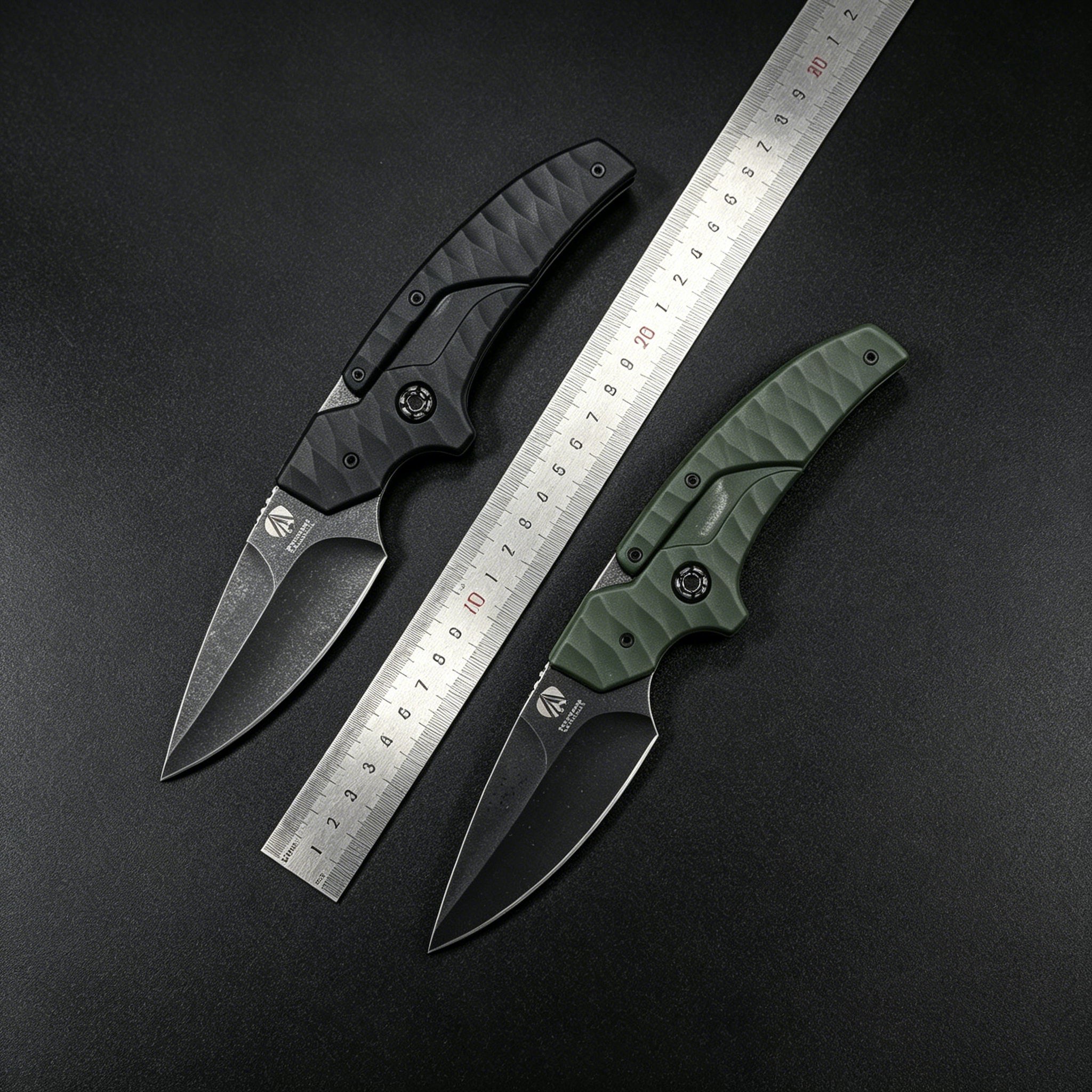 Two open tactical folding knives with black and olive green textured handles and dark blades, displayed with a metal ruler between them on a dark background for size reference.