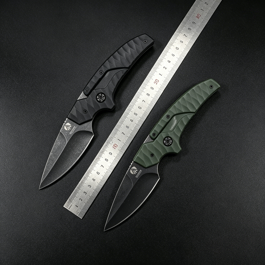 Two open tactical folding knives with black and olive green textured handles and dark blades, displayed with a metal ruler between them on a dark background for size reference.