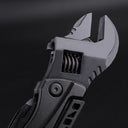 A close-up of a black folding adjustable wrench head, showing the worm gear mechanism for adjusting the jaw width and the textured pivot handle, displayed against a dark background.