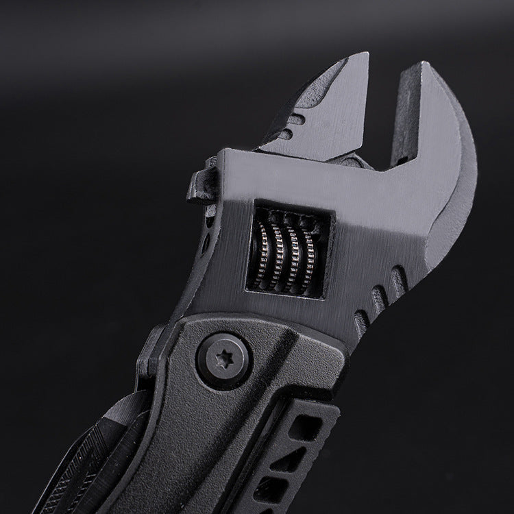 A close-up of a black folding adjustable wrench head, showing the worm gear mechanism for adjusting the jaw width and the textured pivot handle, displayed against a dark background.