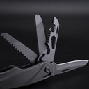 A close-up view of a black folding multi-tool with several attachments deployed, including a serrated saw blade, a grooved file, a bottle opener with wire stripper notches, and a smooth scraping blade.