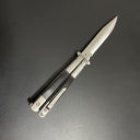 A close-up of an open balisong butterfly knife with a black handle and a silver blade, displayed diagonally on a dark background.