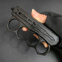 A back view of a closed black knuckle duster OTF knife held by a hand, highlighting the firing button mechanism and the back design of the handle.