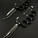 Two open black tactical OTF knives featuring knuckle duster handles with textured grips, displayed on a dark carbon fiber patterned background.