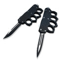 Two open black knuckle duster OTF knives, one plain edge and one serrated, displayed on a white background for product clarity.