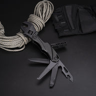 A black folding adjustable wrench multi-tool with multiple blades and tools deployed, displayed on a dark surface next to a coil of paracord and a black nylon sheath.