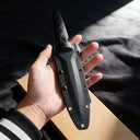 Hand-held black tactical fixed blade knife display, featuring a comfortable Kydex sheath grip and protective guard design to prevent the hand from slipping toward the blade. Ideal for tactical defense and outdoor survival use.