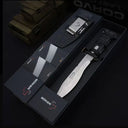 An open black Böker Plus box displaying a silver folding knife with a black handle and a black hard sheath, set against a dark background with "CORVID LAST" lettering visible.