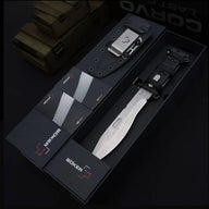 An open black Böker Plus box displaying a silver folding knife with a black handle and a black hard sheath, set against a dark background with "CORVID LAST" lettering visible.