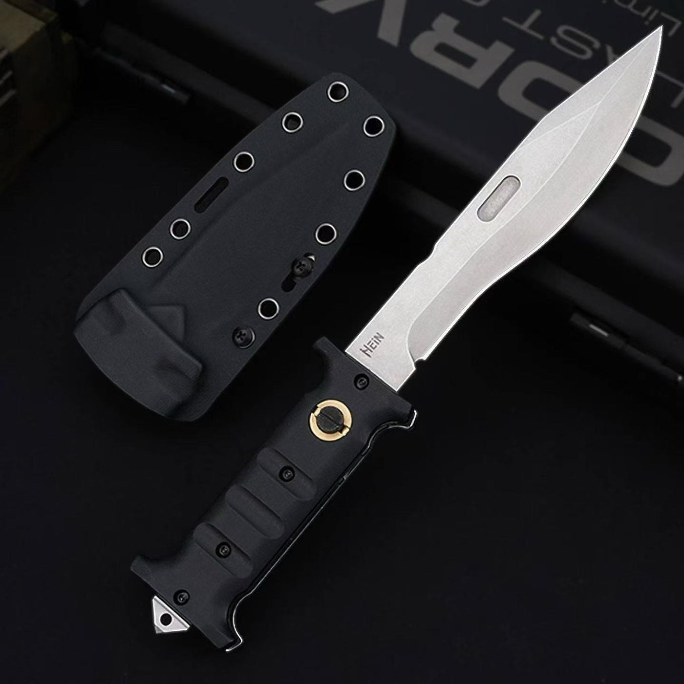 An open Böker Plus folding knife with a black handle featuring finger grooves and a gold pivot, a silver blade with a fuller and "HEIN" engraving, displayed next to a black hard sheath with eyelets on a dark background.
