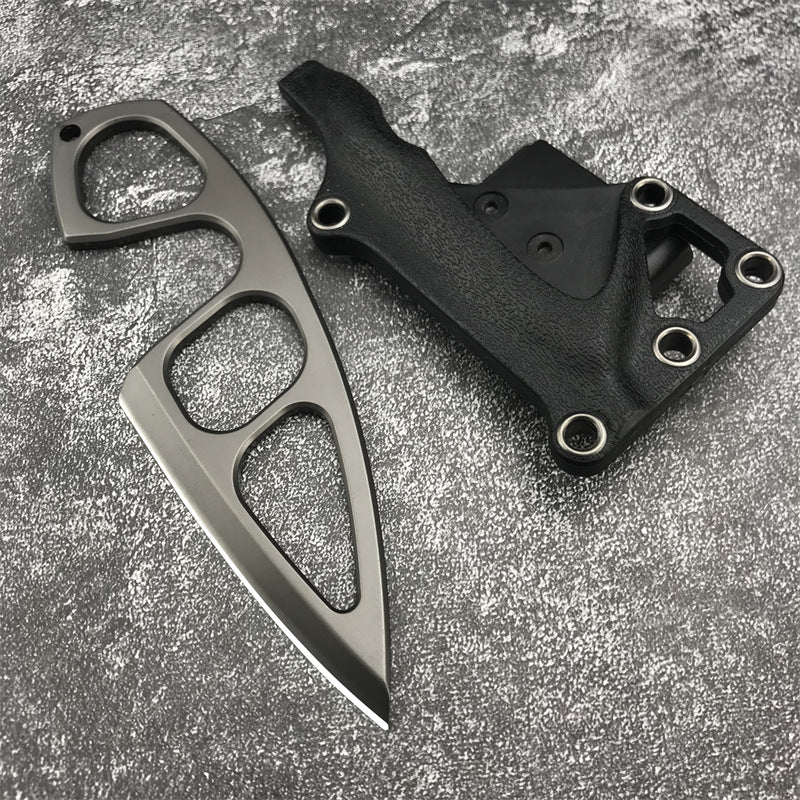 A Böker Plus skeletonized neck knife with a finger ring, displayed separately from its black leather sheath on a mottled grey textured background.