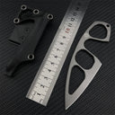 A Böker Plus skeletonized neck knife with its black leather sheath displayed next to a metal ruler on a carbon fiber textured background for size reference.