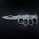 An open folding knuckle duster knife with a grey, red, and black skull and pistol graphic handle, featuring a silver blade with a cutout and the BROWNING logo, on a black background.