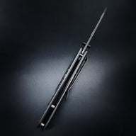 A closed EDC folding knife with a dark handle, silver liners, a pocket clip, and a pointed glass breaker tip, displayed on a dark background.