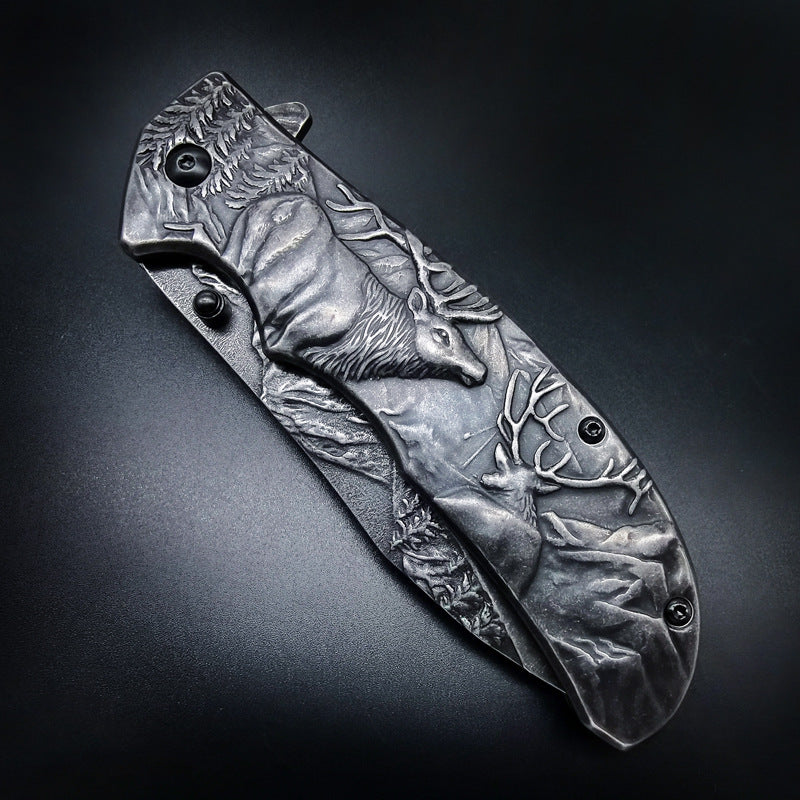 A closed folding knife with deep relief engraving of several deer and forest scenery on the handle and blade, displayed on a dark textured background.
