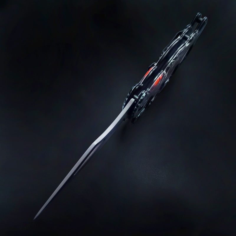 A closed folding knuckle duster knife viewed from the back, showing the handle profile, visible blade spine, and graphic details, on a dark background.