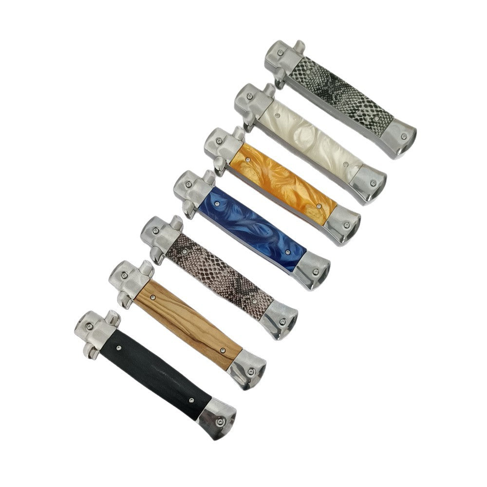  A collection of closed stiletto-style folding knives with various handle patterns including wood, black, blue resin, orange resin, white pearl, and snakeskin textures.
