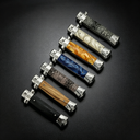  A collection of closed stiletto-style folding knives with various handle patterns including wood, black, blue resin, orange resin, white pearl, and snakeskin textures.