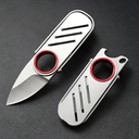 An open and a closed EDC keychain folding knife with a silver stainless steel body and red ring, displayed on a dark textured surface.