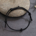 A black wearable tactical handcuff key displayed on a natural stone surface, highlighting its discreet and durable design for everyday carry.