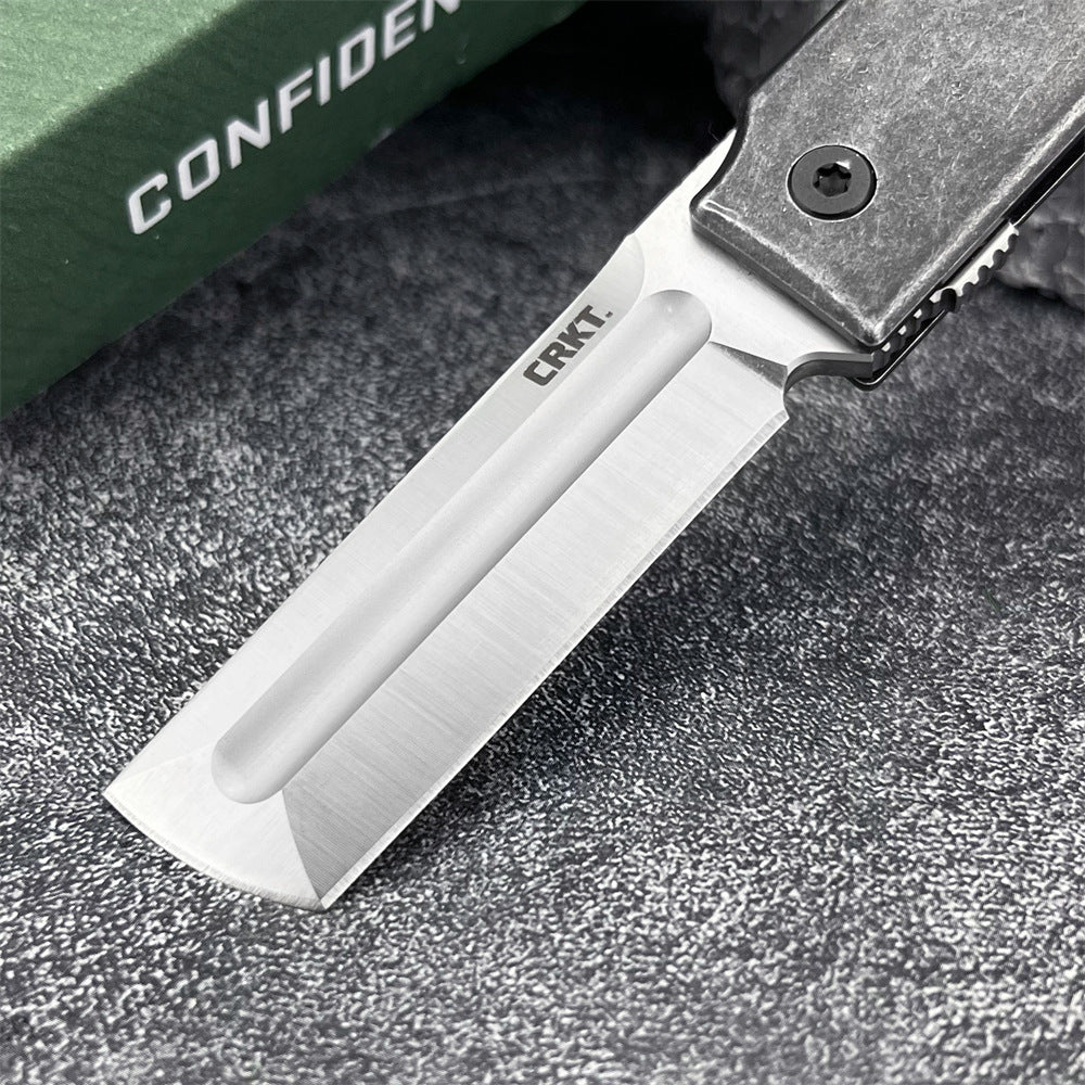 A close-up of the silver tanto blade and edge on a CRKT folding knife, with the engraved CRKT logo clearly visible.