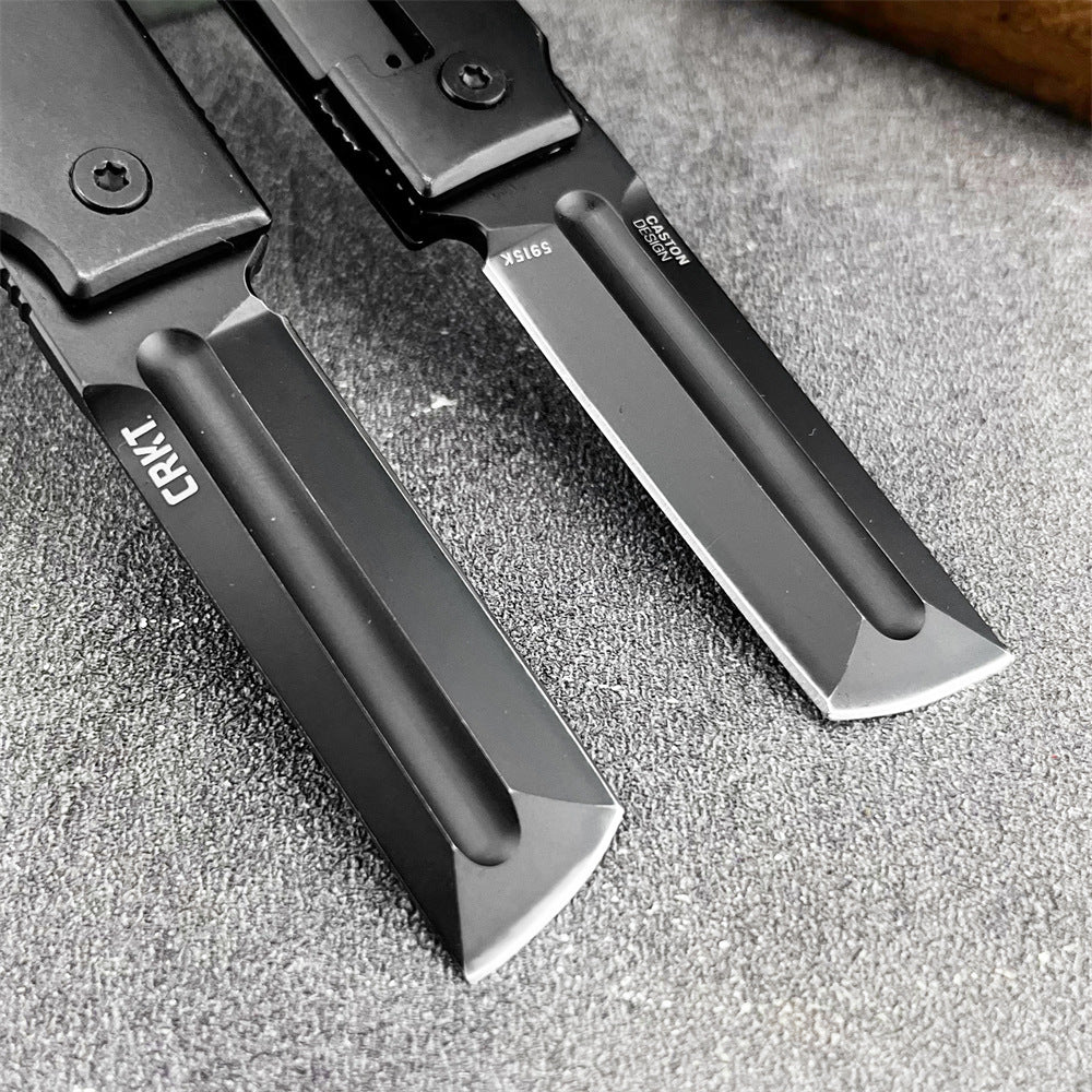A close-up of two CRKT knife blades, one with a grey finish and one with a black finish, showing the steel markings and CRKT logo.