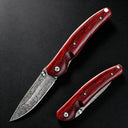 An open and a closed folding knife featuring a patterned damascus steel blade and polished red wooden handles, displayed on a dark textured surface.