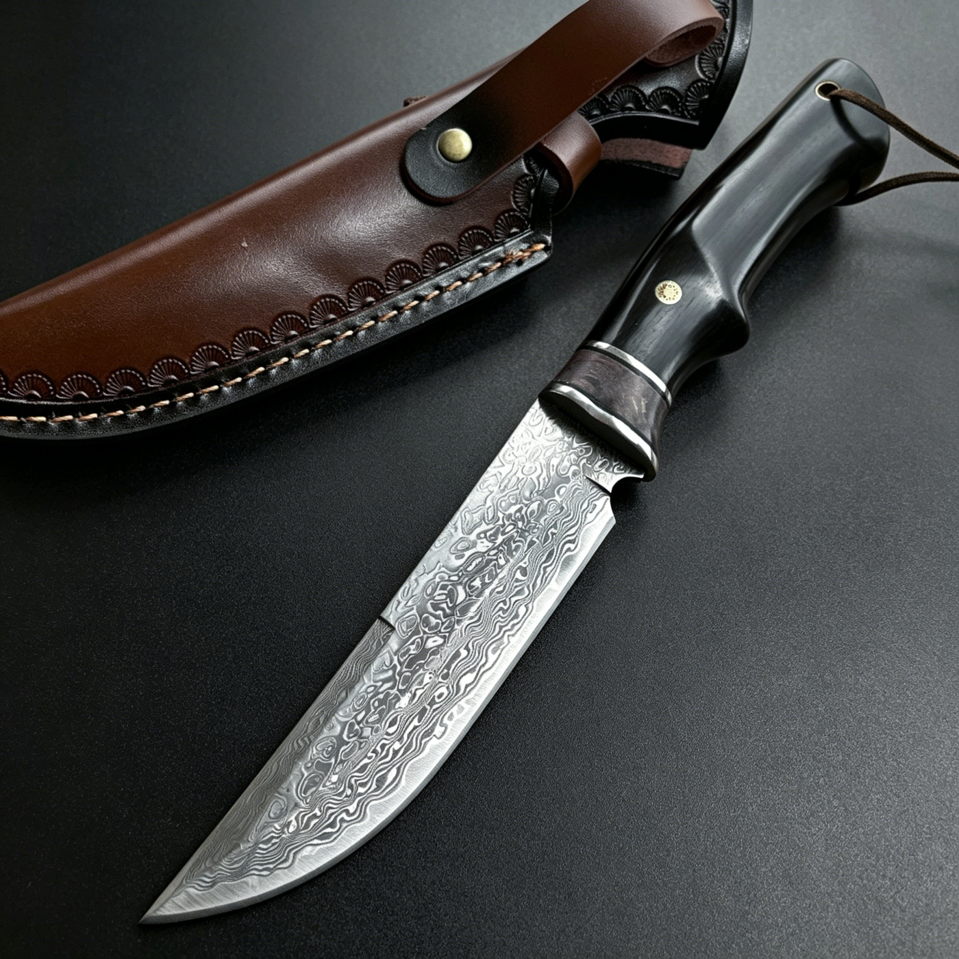 Handmade Damascus steel hunting knife with black wood handle and brass guard, paired with a hand-carved brown leather sheath featuring a distinctive turquoise button, designed for outdoor use or as a collector's gift.