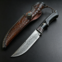 Handmade Damascus steel hunting knife with black wood handle and brass guard, paired with a hand-carved brown leather sheath featuring a distinctive turquoise button, designed for outdoor use or as a collector's gift.