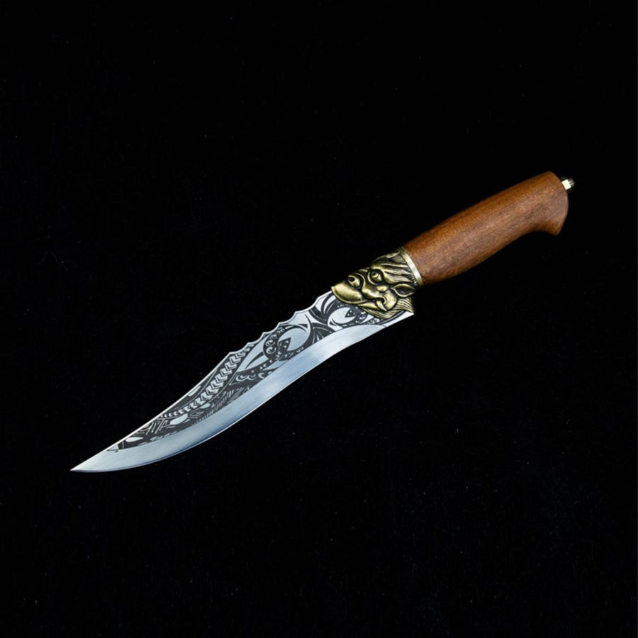 A side view of an engraved curved fixed blade knife with a wooden handle, brass animal head guard, and patterned blade, displayed on a dark background.