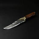 An engraved fixed blade knife with a feather-patterned silver blade, a brass bolster, and a wooden handle, displayed diagonally on a black background.