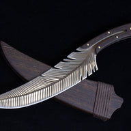 An engraved feather blade knife crossed over its dark wooden sheath, displaying the matching wood grain on the handle and sheath.