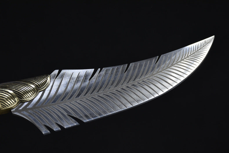 A close-up of a custom fixed blade knife showing intricate feather engraving on the silver blade and a ridged brass bolster, displayed on a dark background.