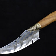 A full side view of a curved fixed blade knife with a feather-patterned blade, a ridged brass bolster, and a polished wooden handle, displayed on a dark background.