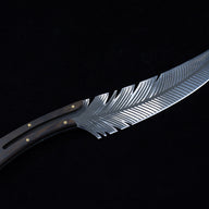 A full profile view of a curved fixed blade knife featuring detailed feather engraving, a dark wood handle with brass pins, and a silver lanyard hole.