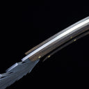 A side profile view of a custom fixed knife, showcasing the dark wood handle, silver blade with feather engraving, and brass pins against a dark background.