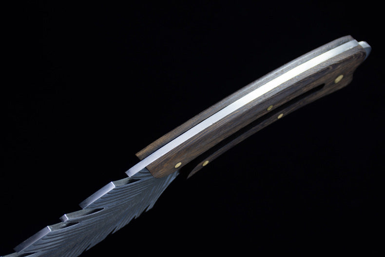 A side profile view of a custom fixed knife, showcasing the dark wood handle, silver blade with feather engraving, and brass pins against a dark background.