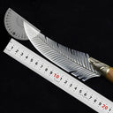 A curved feather blade knife displayed on a dark background with a metal ruler and a plastic protractor to show its dimensions and blade angle.