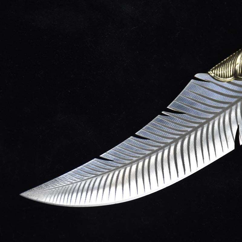 A close-up of an engraved fixed blade knife showing the intricate feather pattern and ridged brass bolster details against a dark background.