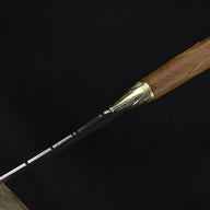 A close-up of the rear section of the blade on a custom fixed knife, highlighting the transition from the brass bolster to the detailed feather engraving.