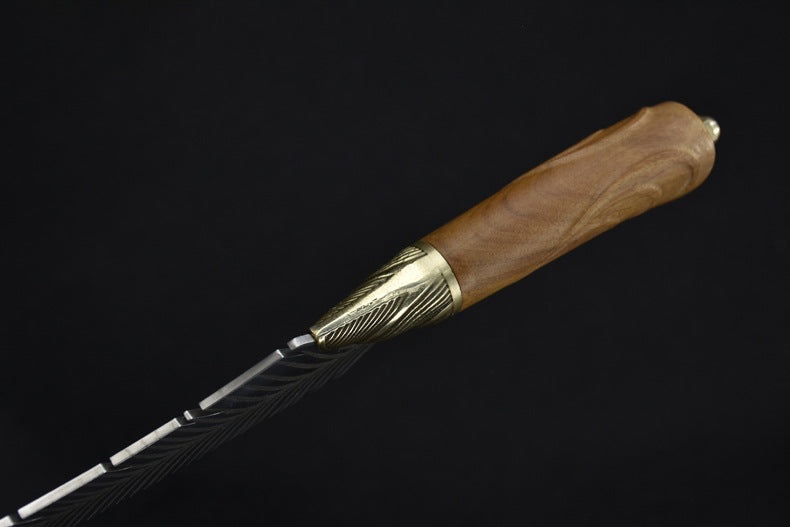 An extreme close-up of a fixed blade knife, emphasizing the intricate ridged texture of the brass bolster meeting the flowing silver feather engraving on the blade.